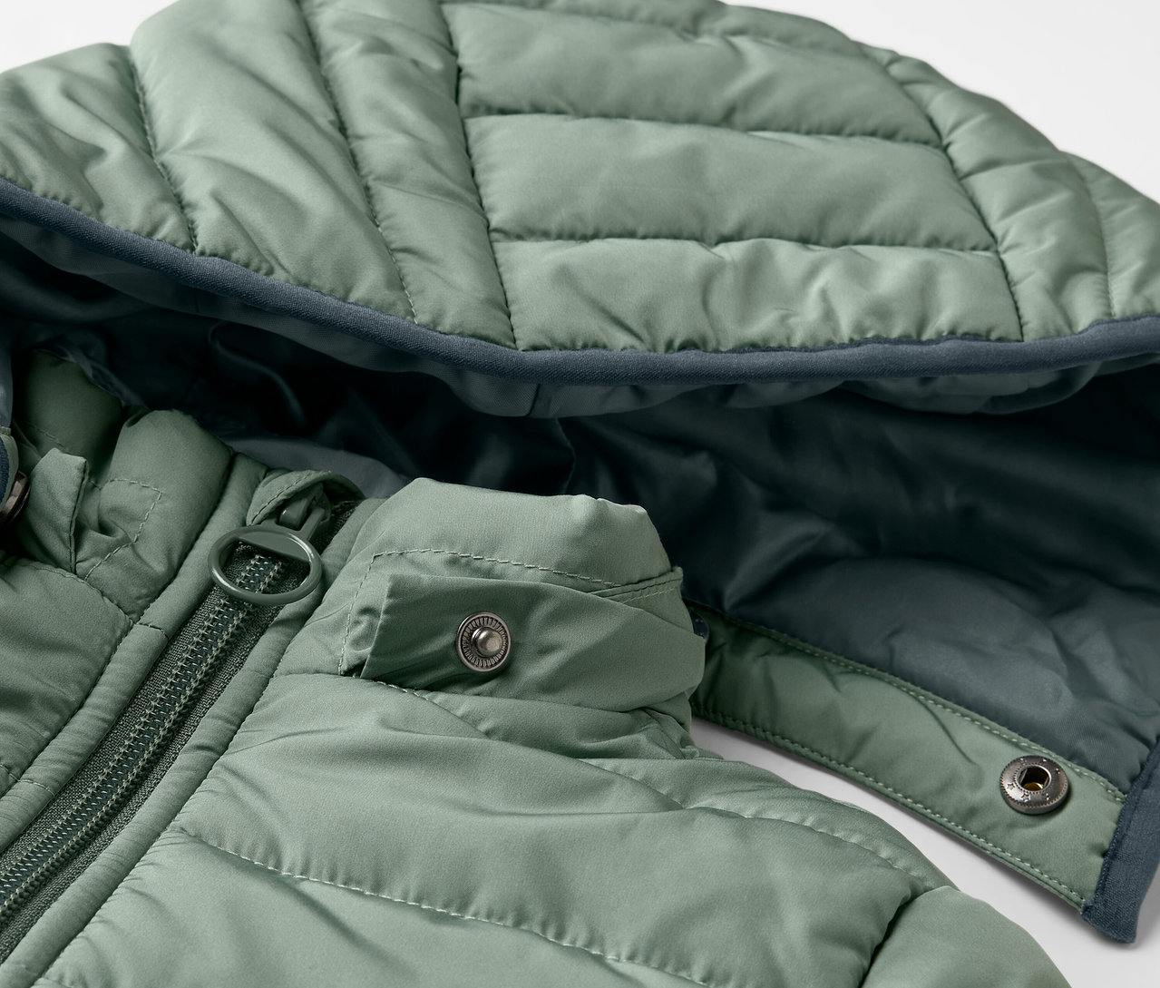 Detail zelené dětské prošívané bundy.