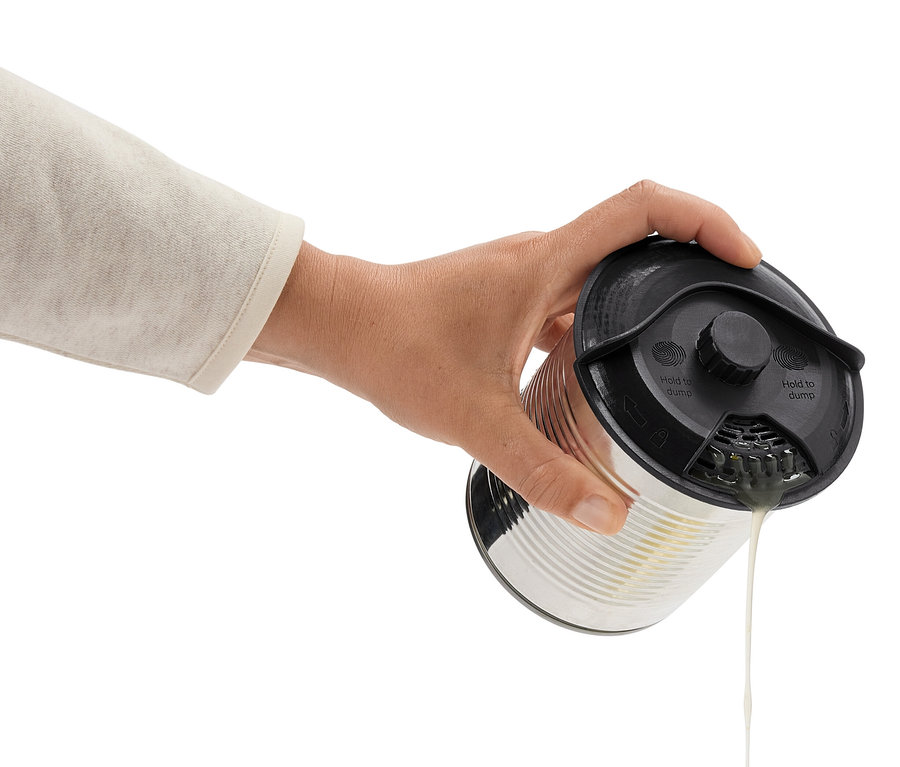 Ruka naklání plechovku s černým víkem a vylévá tekutinu.