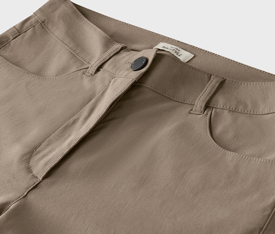 Detail béžových kalhot s knoflíkem.