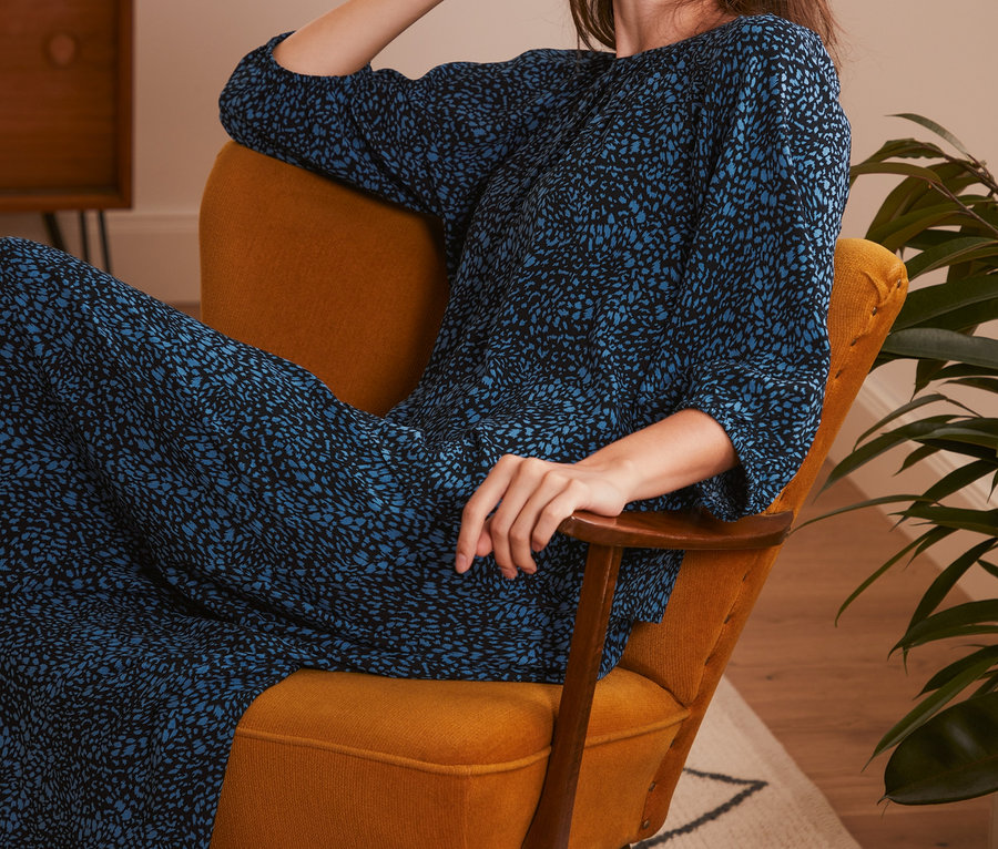 Žena sedí v křesle a má na sobě halenku s potiskem.