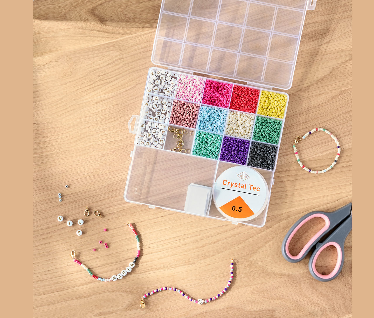 Otevřená sada DIY korálků s barevnými korálky, šňůrkou a nůžkami na dřevěném stole.