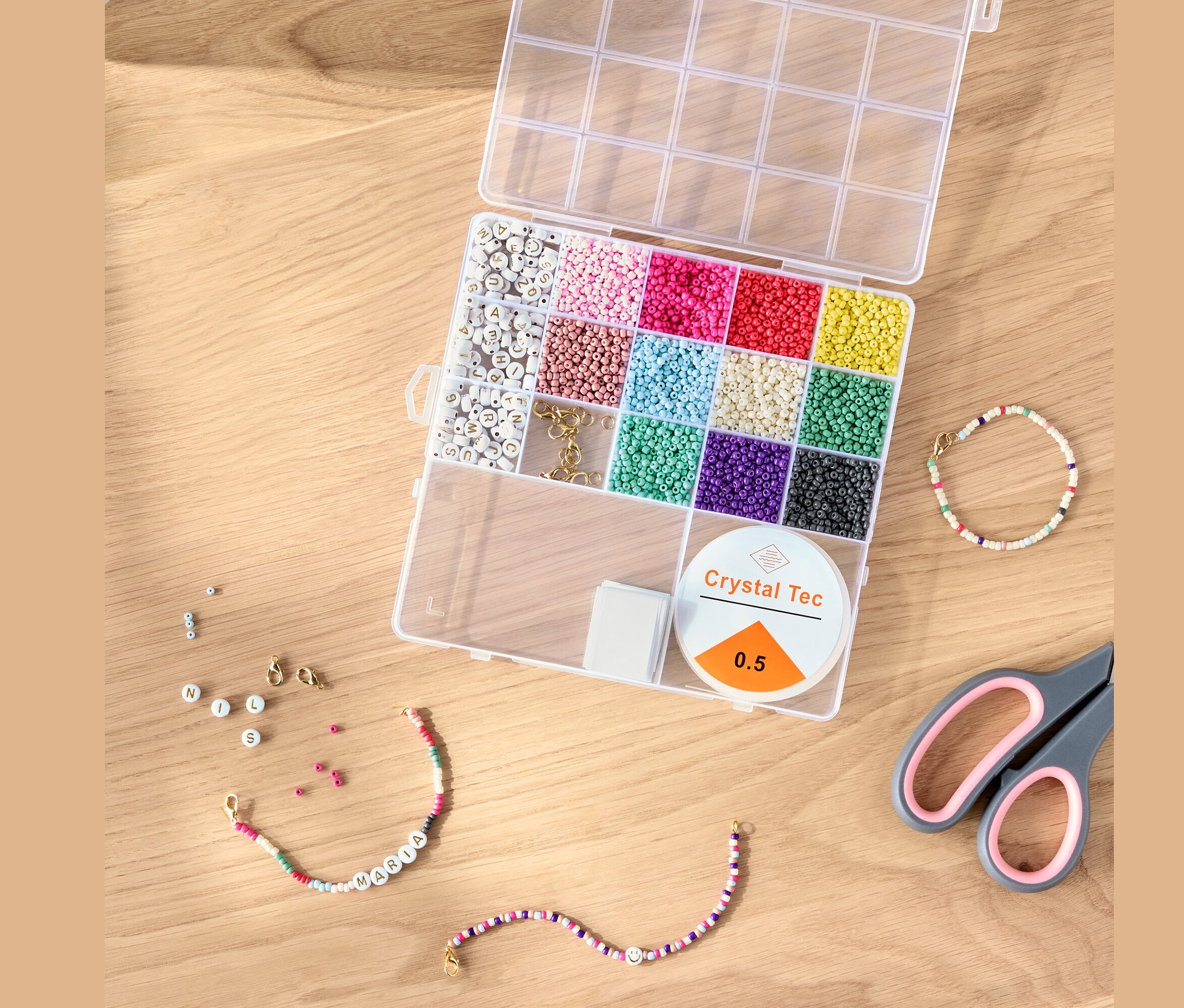 Otevřená sada DIY korálků s barevnými korálky, šňůrkou a nůžkami na dřevěném stole.