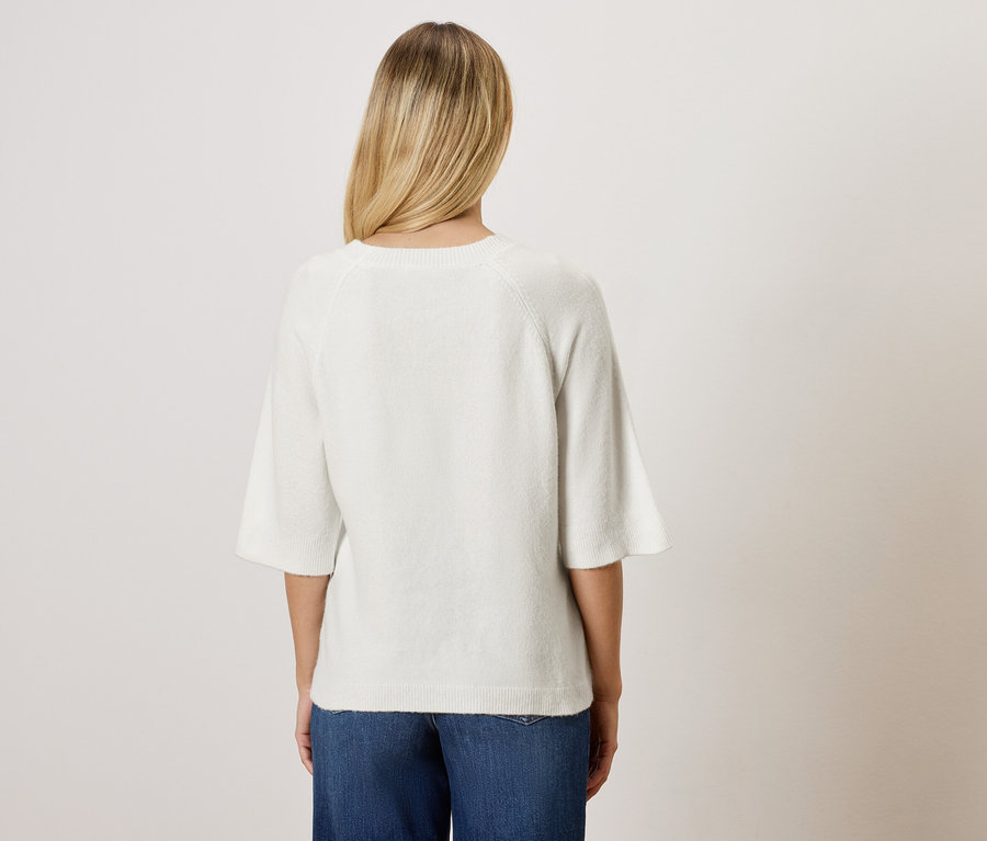 Zezadu pohled na ženu s blond vlasy v bílé blůze a modrých džínách.