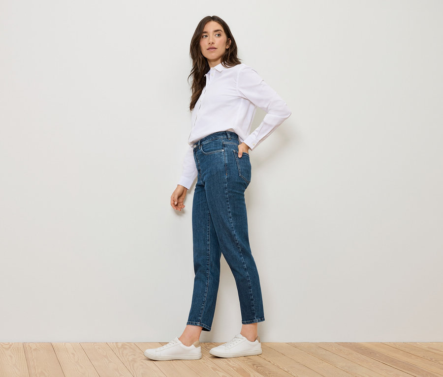 Žena pózuje v modrých Mom Jeans – Fit »Nyla« a bílé košili.