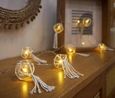 LED světelný řetěz s koulemi leží na dřevěné komodě.