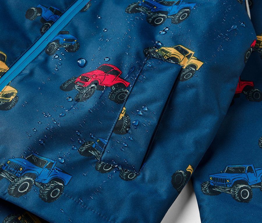 Detail dětské termo bundy do deště s potiskem monster trucků.