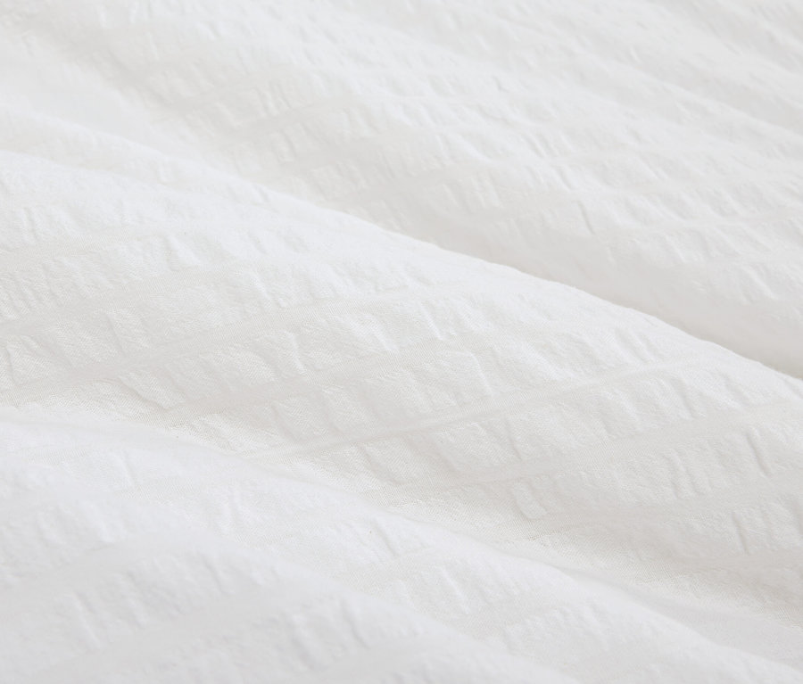 Detailní pohled na bílou látku s texturou.