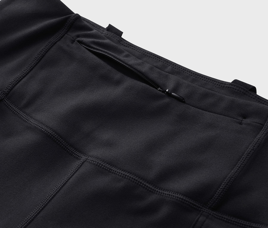 Detailní záběr na černé outdoorové legíny s kapsou na zip.