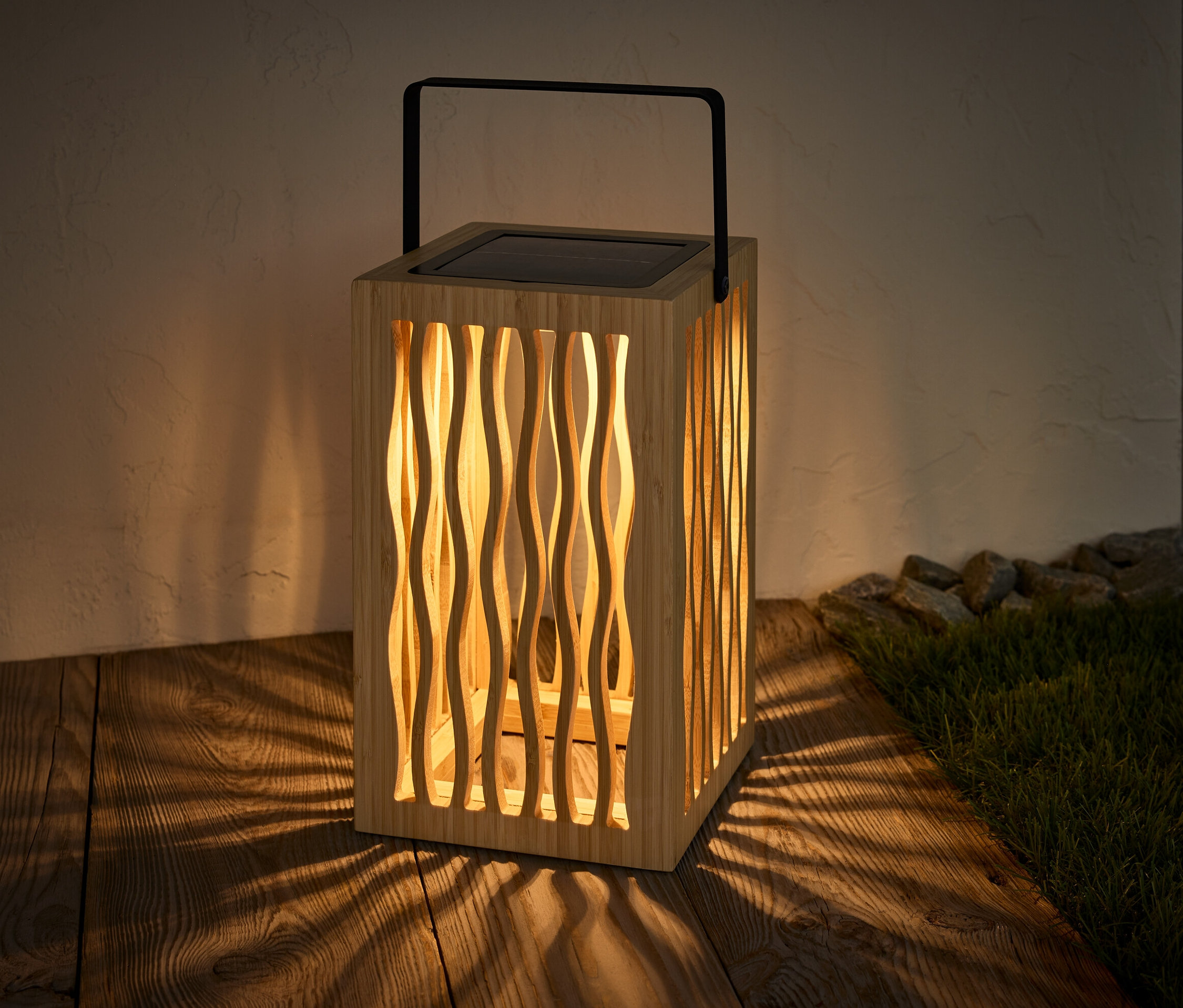 Solární lucerna stojí na dřevěné podlaze a vrhá stín.