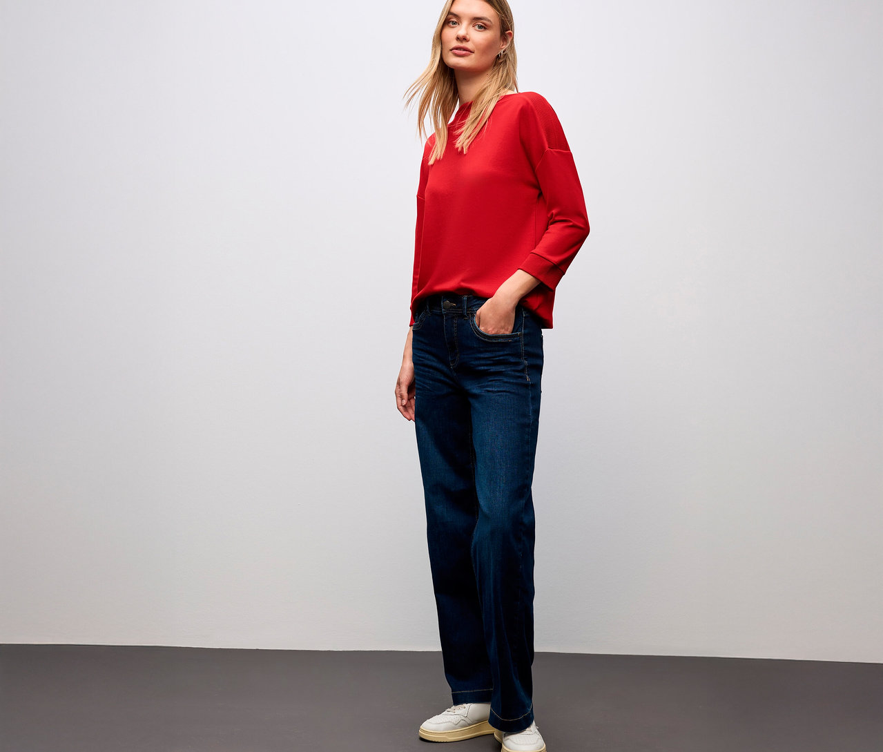 Žena v červeném tričku Street One s žebrovanými detaily a džínách.