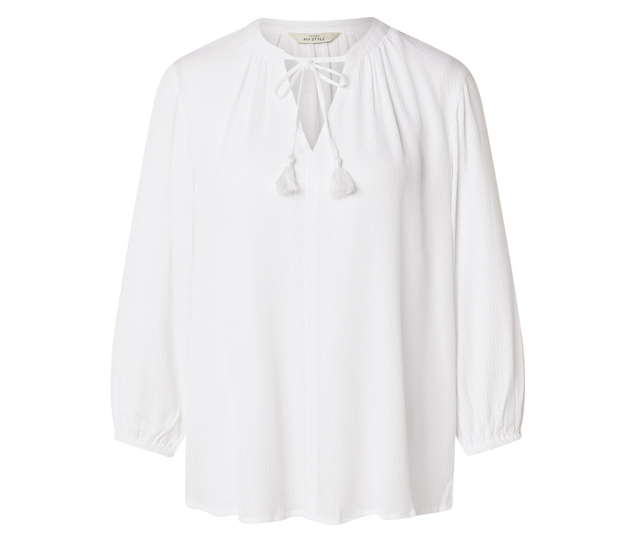 Na bílém pozadí je vidět bílá halenka s dlouhým rukávem se šněrováním a střapci.