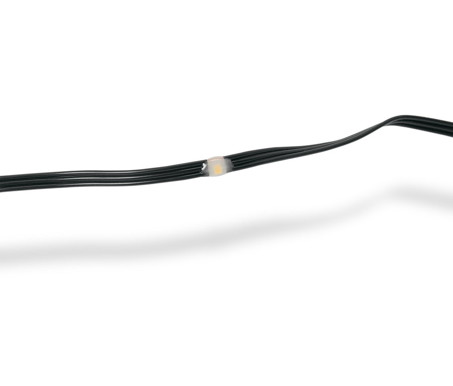 Detailní záběr černého světelného řetězu s jednou LED žárovkou, která je průsvitná bílá.