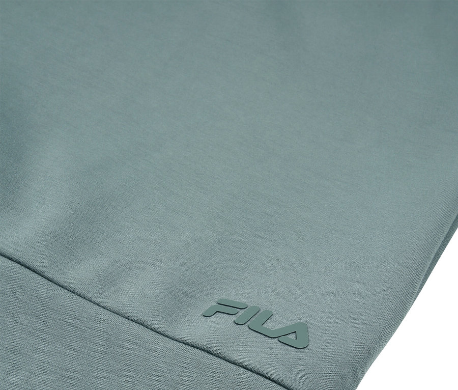 Detail světle modrozeleného oděvu s logem FILA.