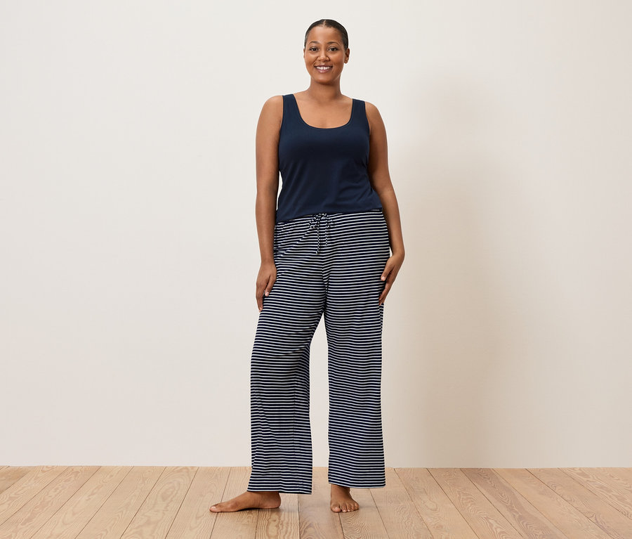 Žena má na sobě modré tílko a pruhované kalhoty.