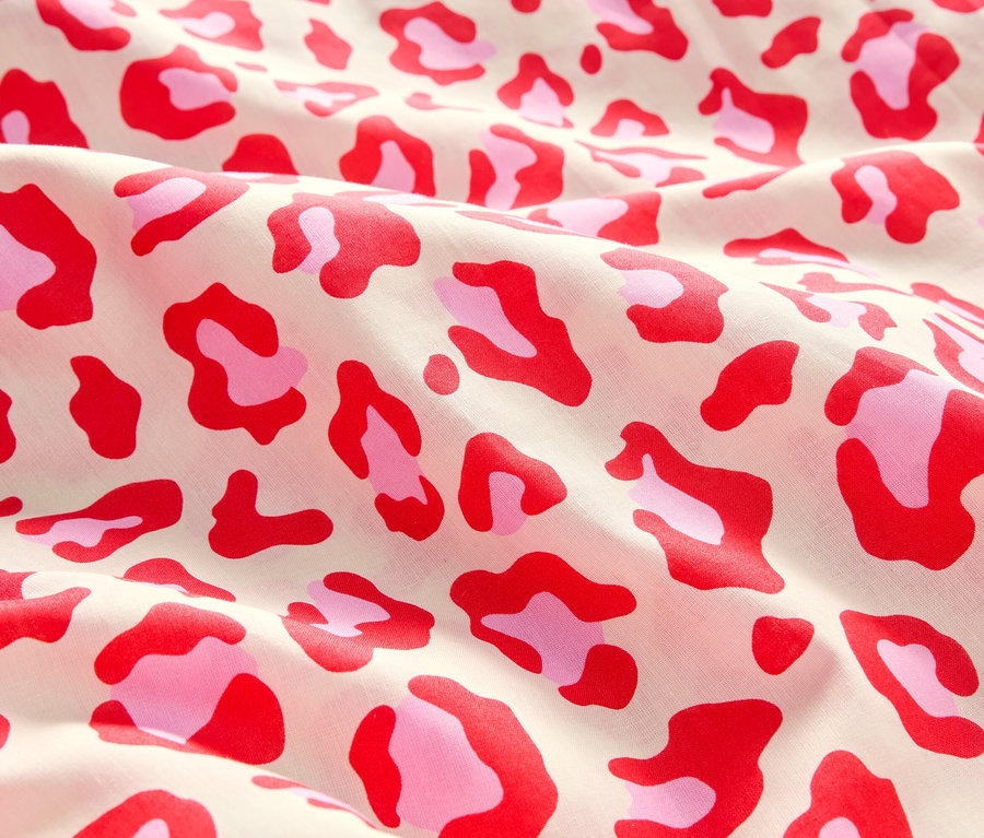 Detail látky s červeným a růžovým leopardím vzorem.