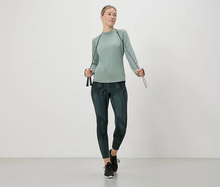 Žena ve sportovním oblečení drží v rukou švihadlo.