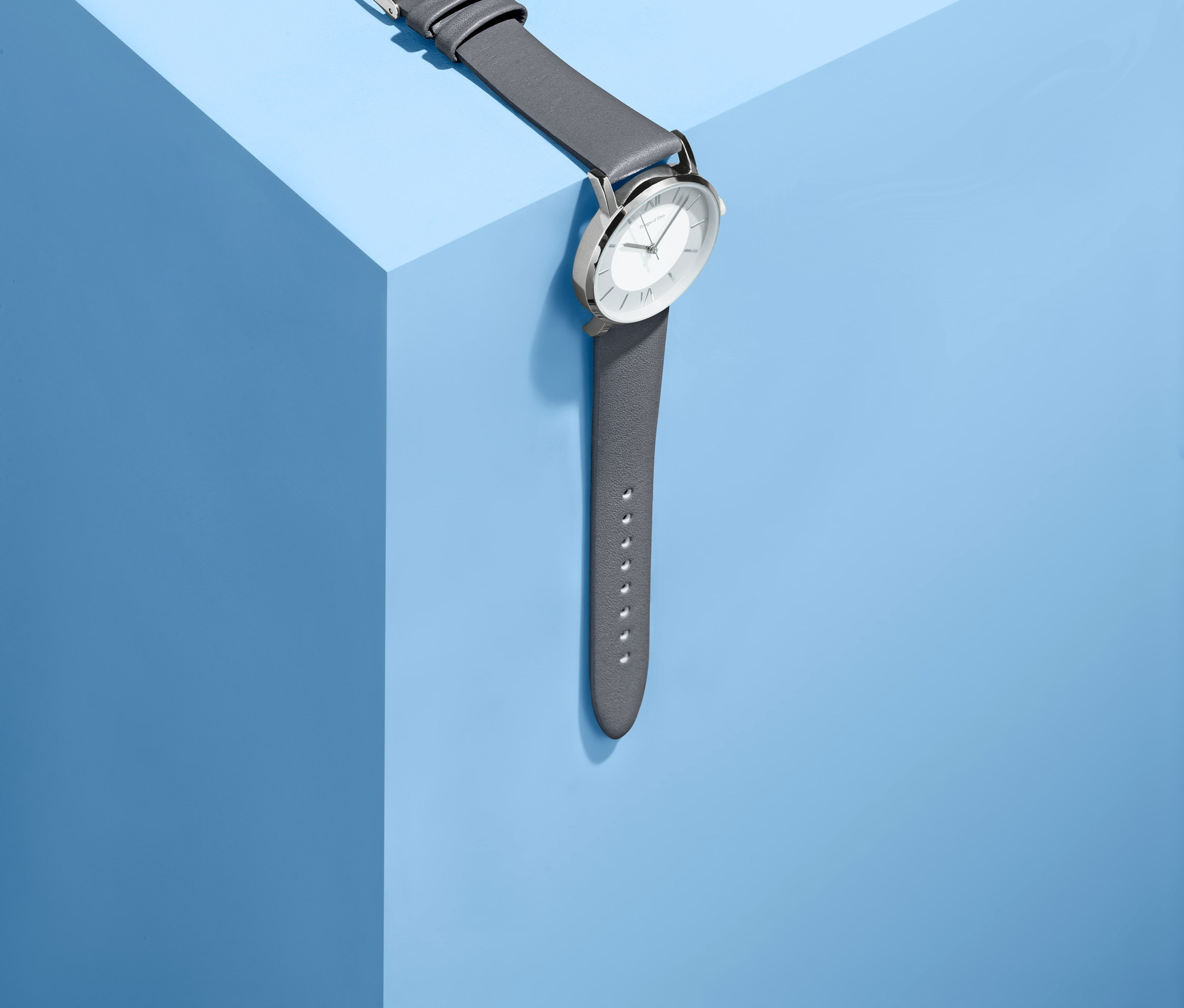 Dámské hodinky s koženým řemínkem leží na modrém povrchu.