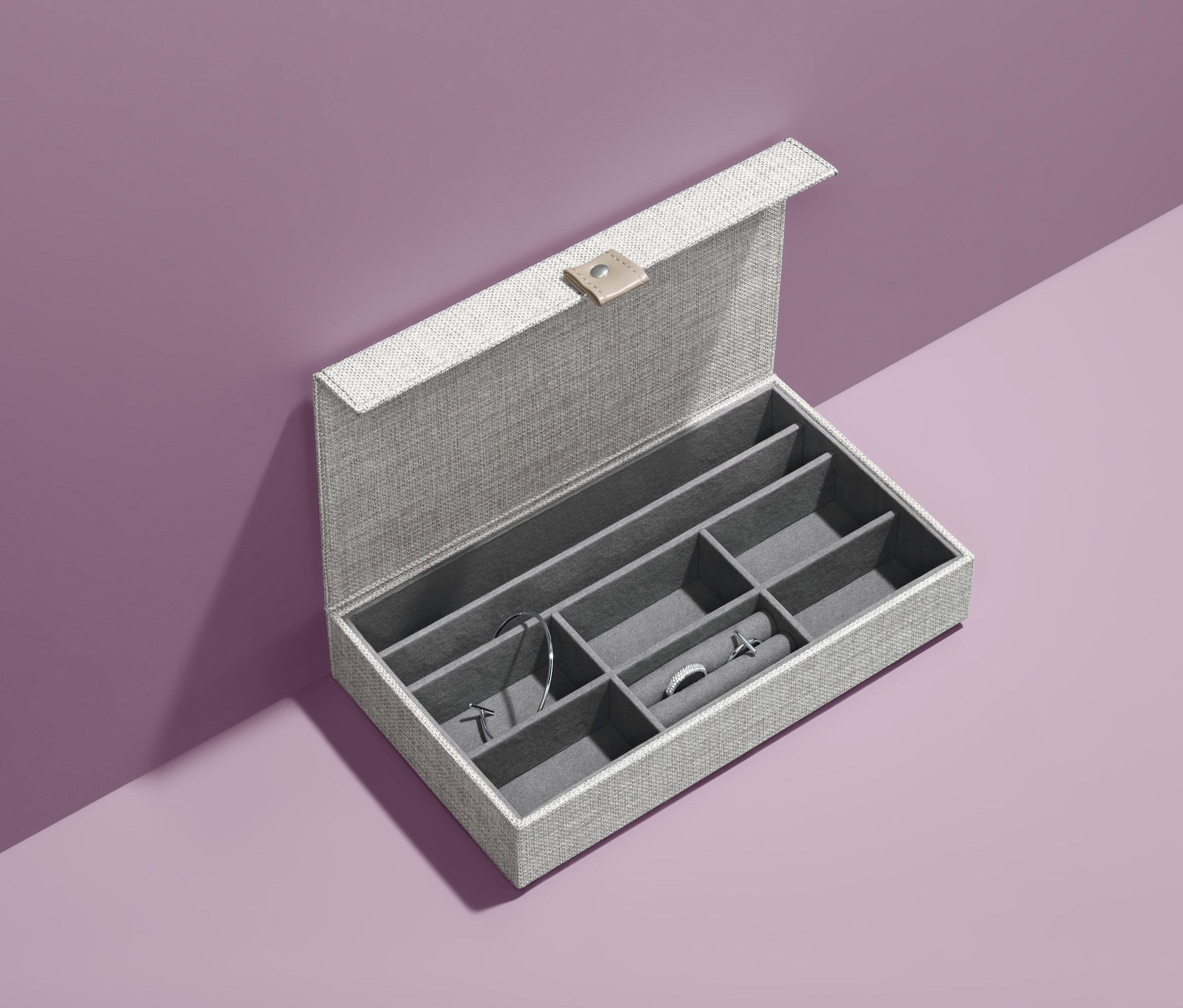Otevřená šperkovnice se šperky na fialovém pozadí.