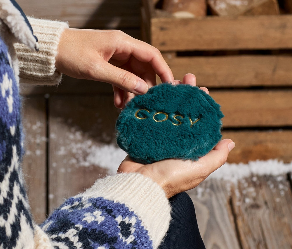 Žena drží v ruce dva hřejivé polštářky do kapsy.