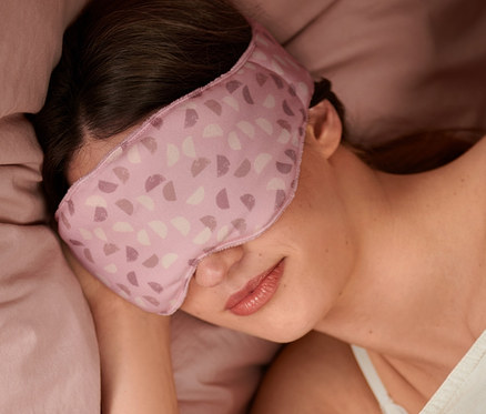 Žena spí v posteli s maskou na spaní.