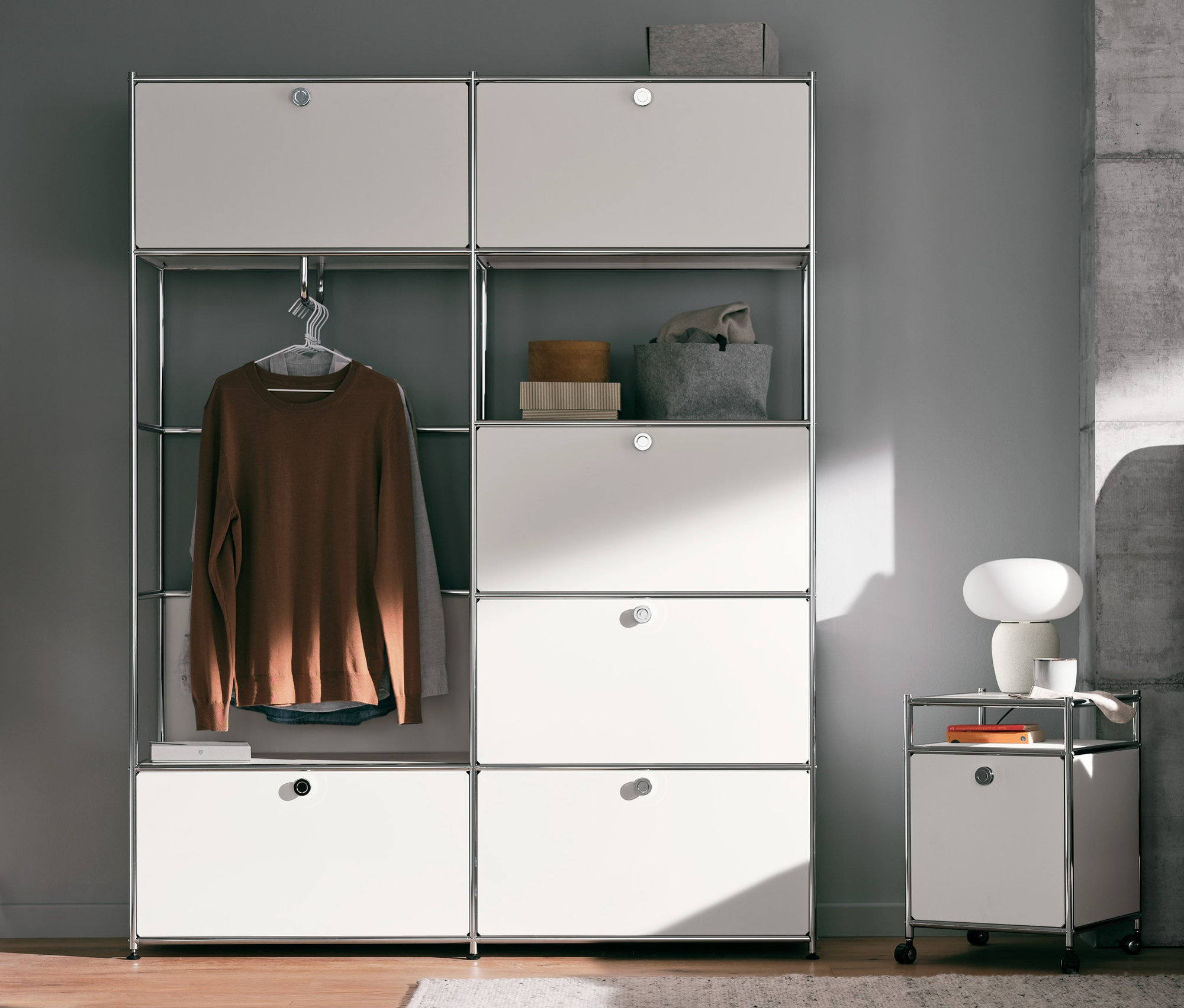 Ložnice s kovovou skříní CN3, bílým kovovým kontejnerem na kolečkách CN3 a stolní lampou se skleněným stínítkem.