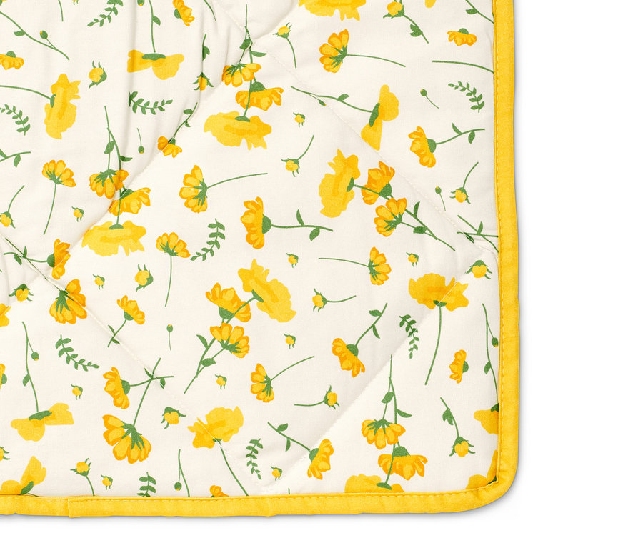 Detail vatované piknikové deky s květinovým vzorem.