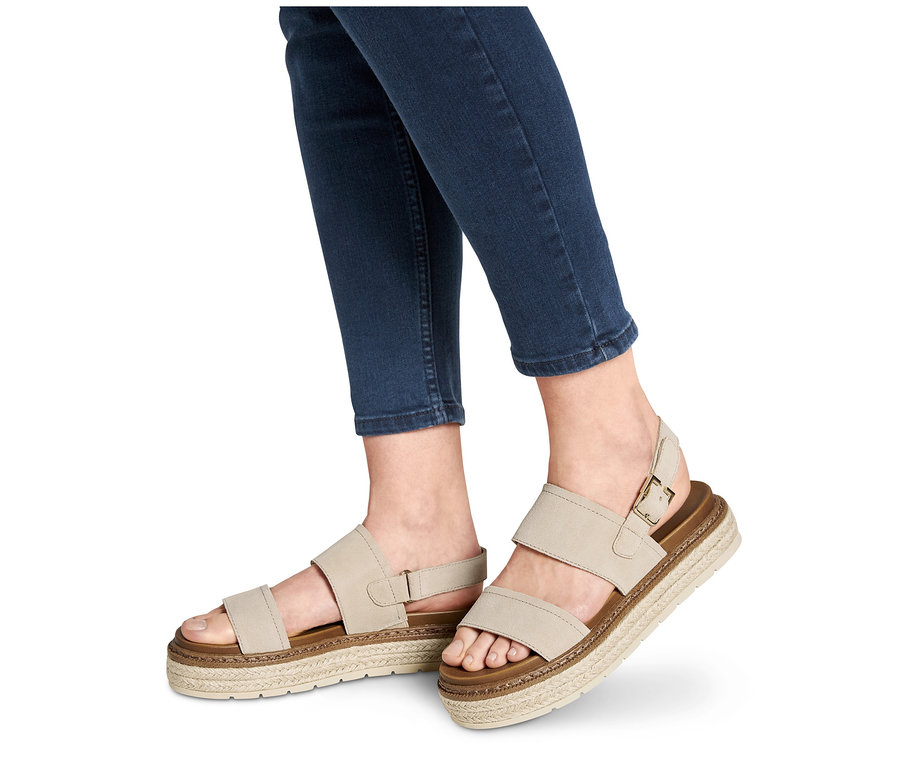 Nohy v džínových kalhotách obuté do kožených sandálů na platformě.