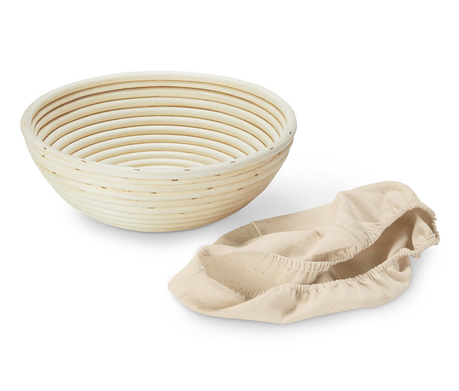 Prázdná kulatá ošatka na kynutí těsta a béžový látkový obal.