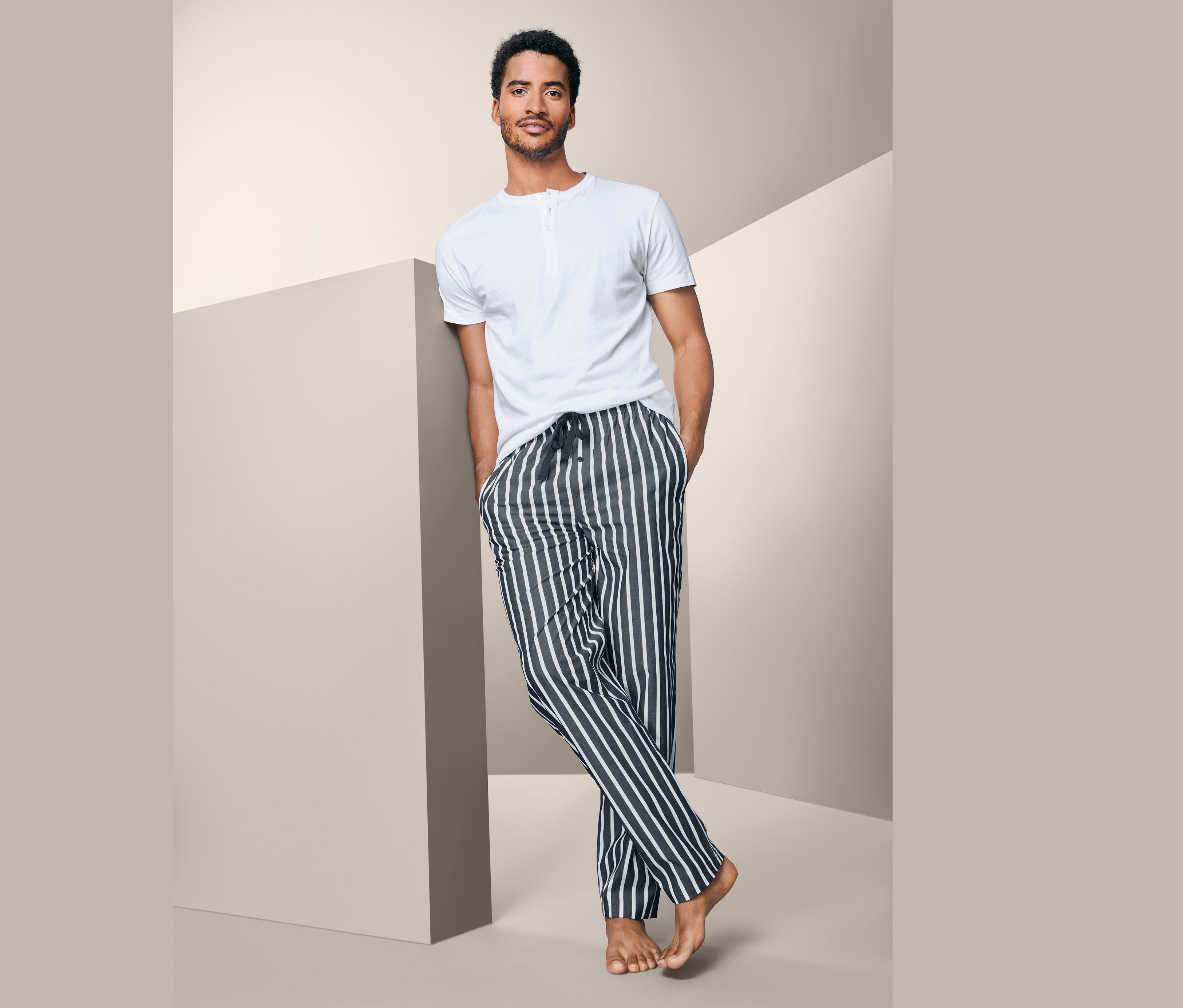 Muž opřený o zeď má na sobě pyžamo.