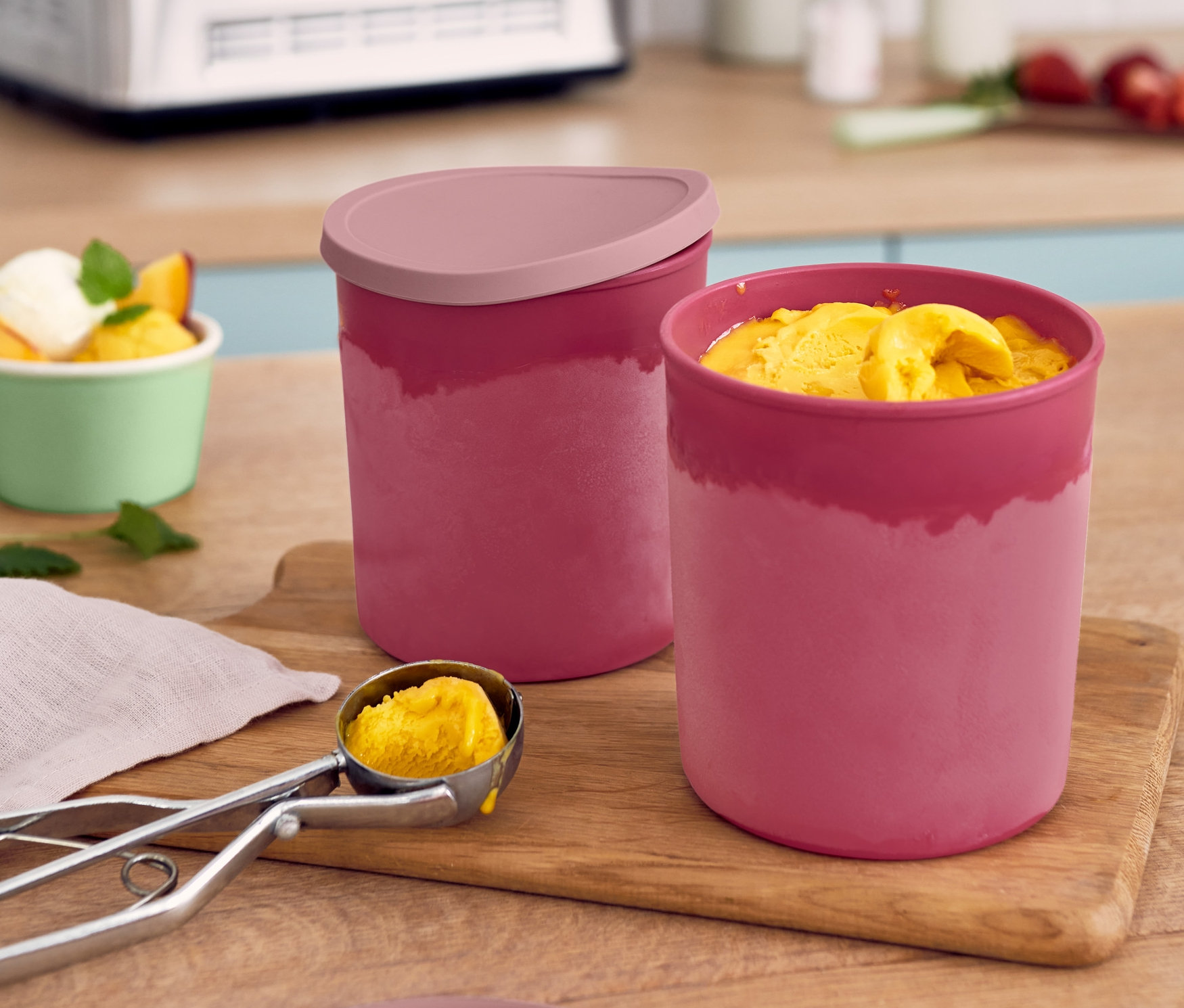 Dvě červené dózy do mrazničky a lžíce zmrzliny na dřevěném prkénku.