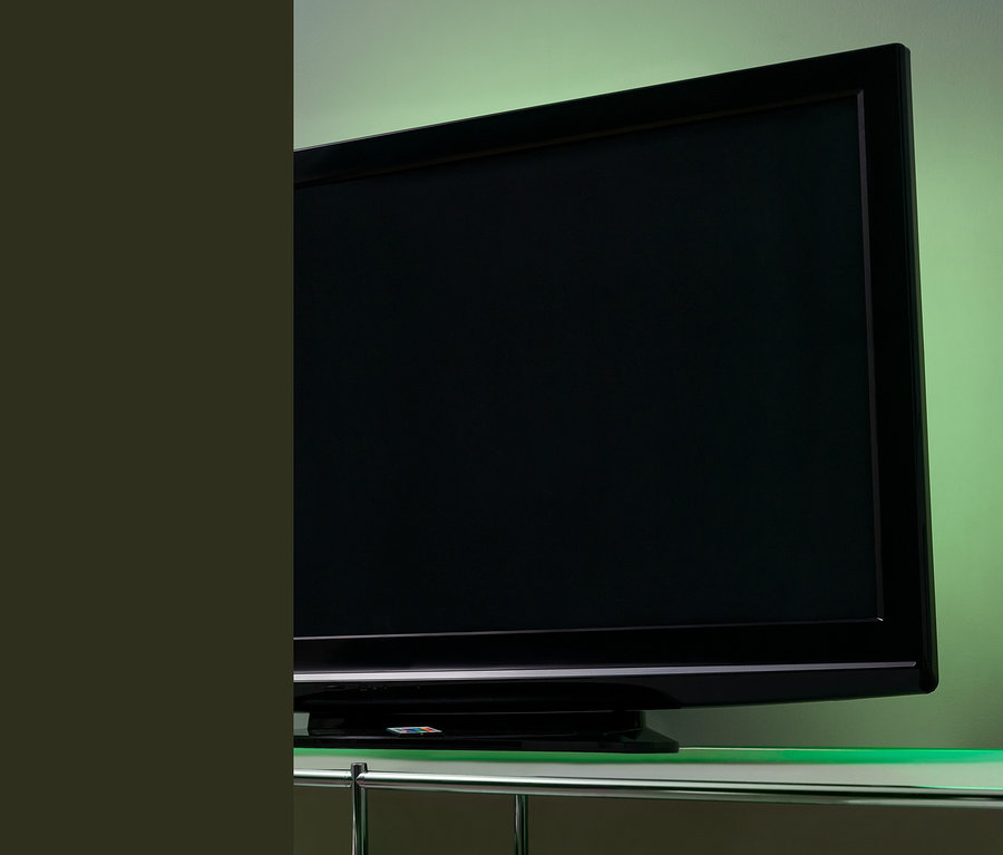 Černá televize s LED podsvícením pro TV na skleněném stolku.