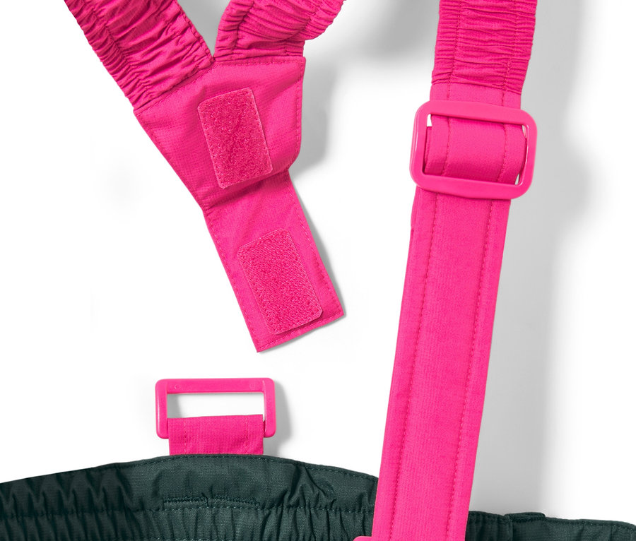 Detail dětských lyžařských kalhot tmavě zelené barvy s růžovými nastavitelnými šlemi.