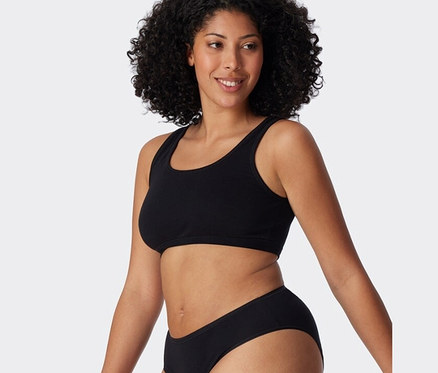 Žena má na sobě černou podprsenku SCHIESSER s biobavlnou z dvoudílné sady.