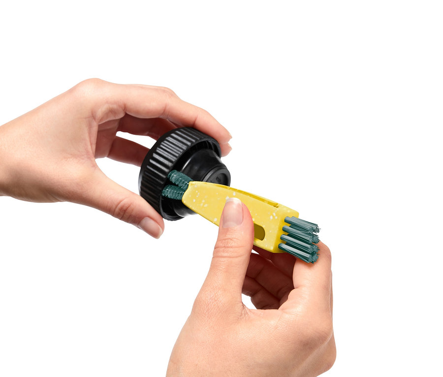 Žena čistí černý uzávěr pomocí žlutého multifunkčního kartáče 3 v 1.