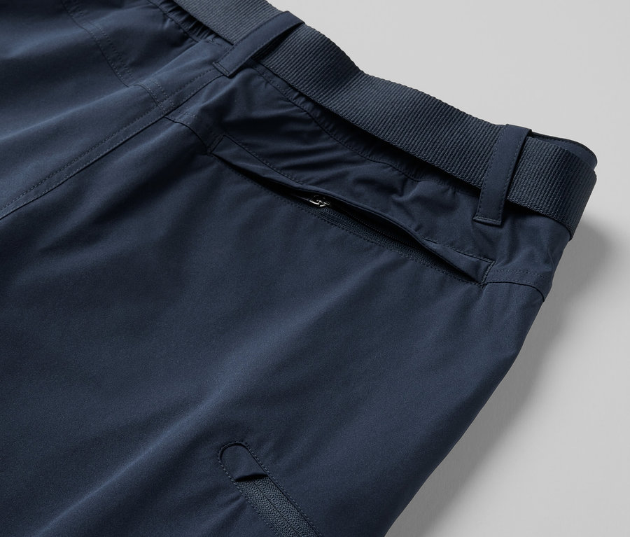 Detail modrých funkčních kalhot 2 v 1 s kapsami na zip a páskem.