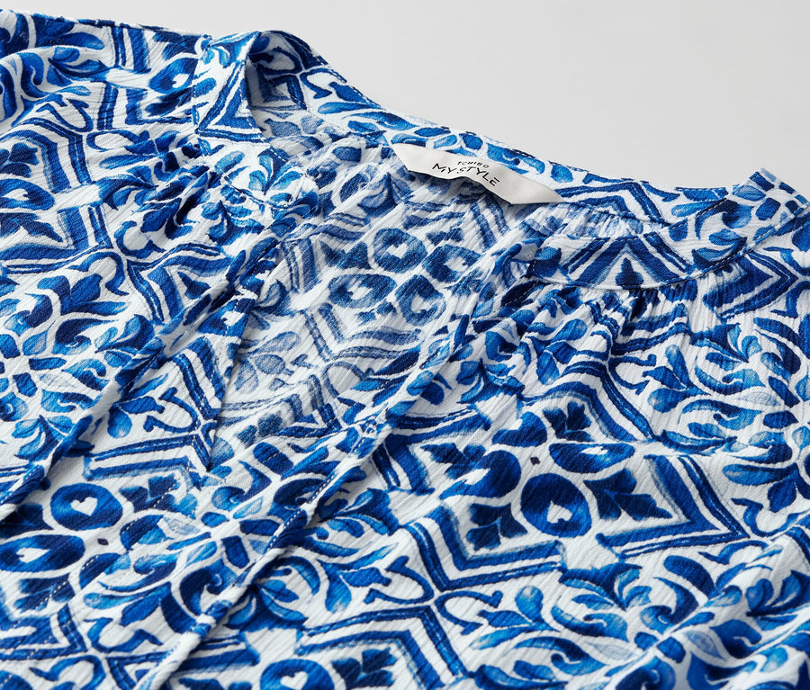 Detail modré tunikové halenky s potiskem.