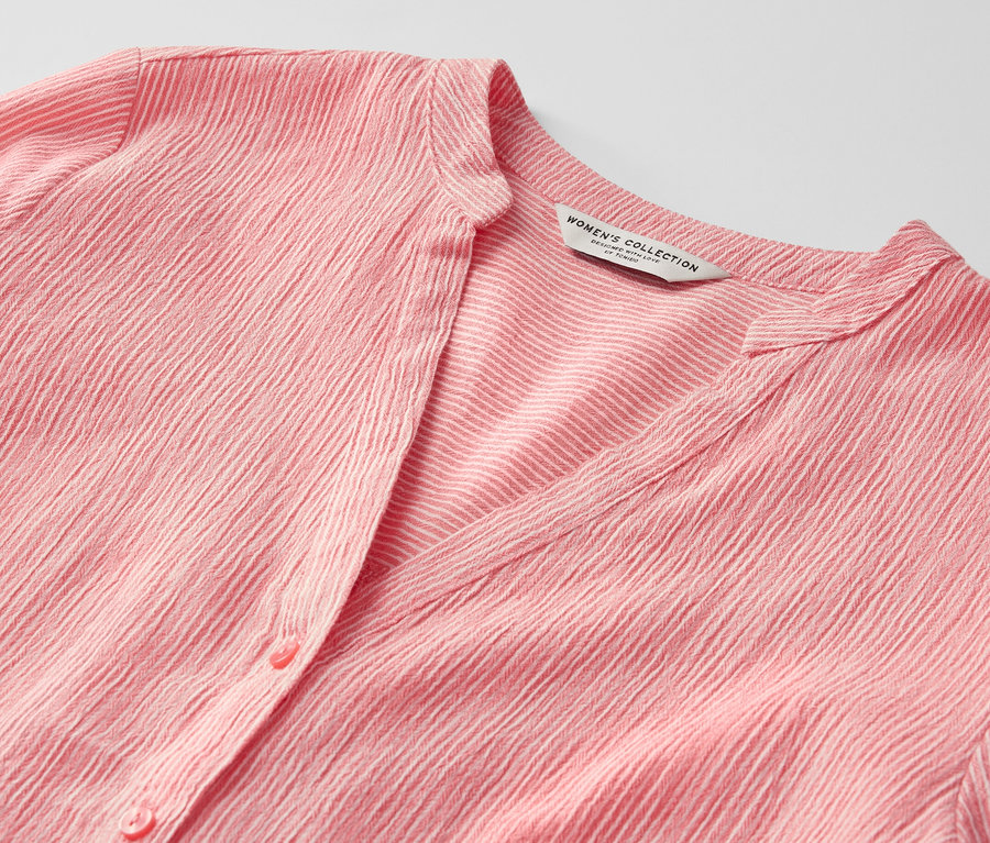 Detail korálové tuniky s proužky.