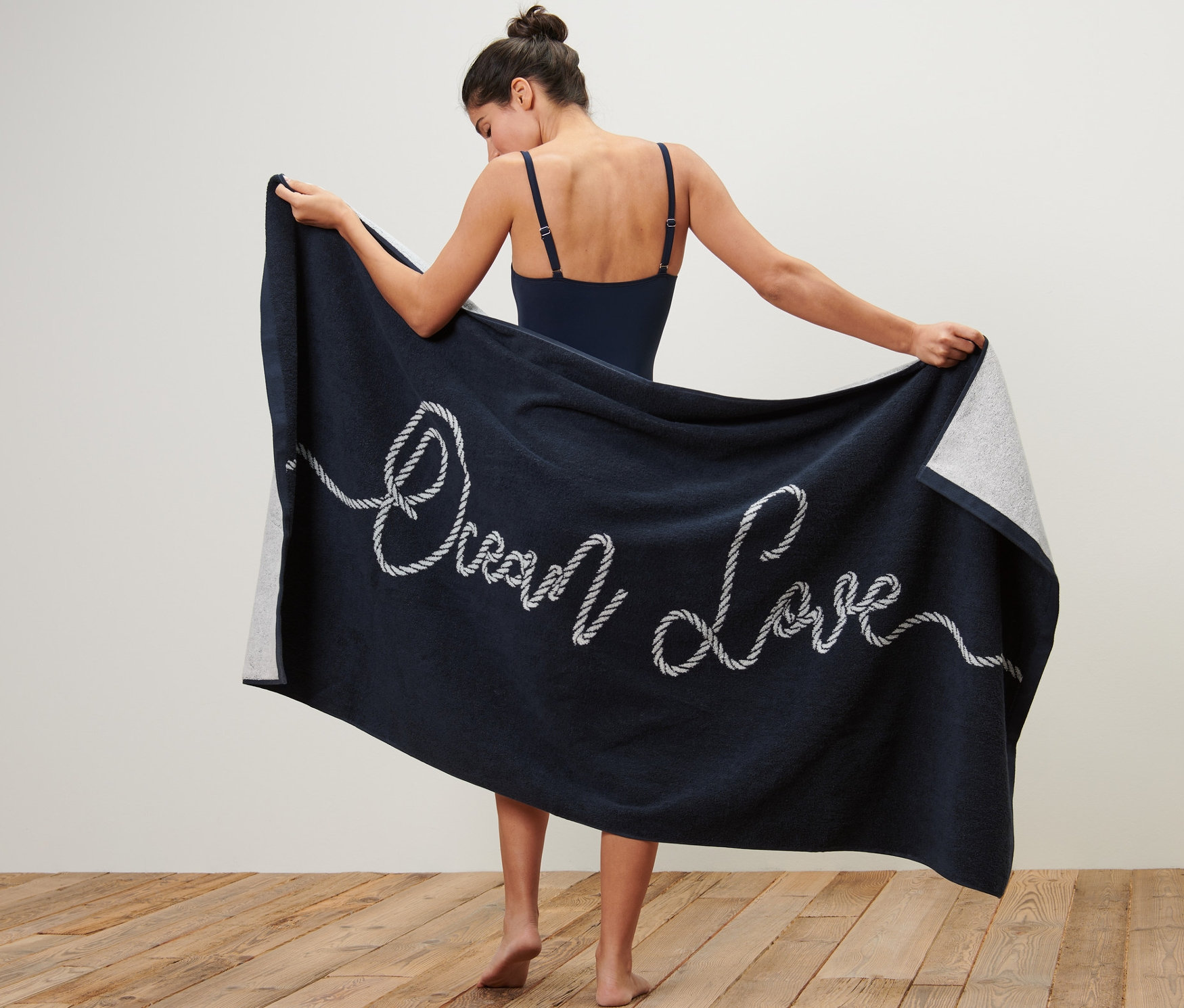 Žena drží extra velkou osušku s nápisem "Ocean Love".