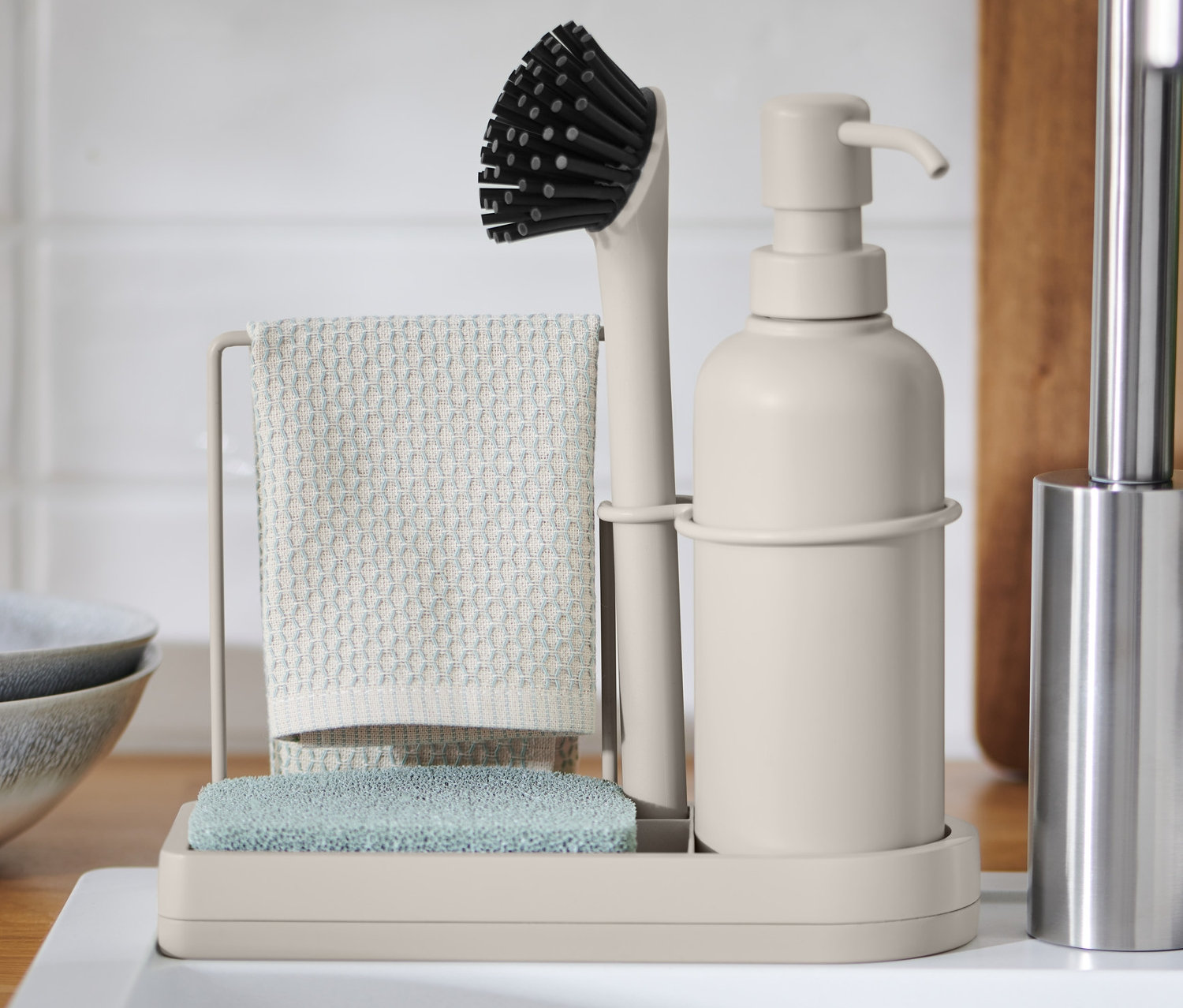 Organizér k dřezu s kartáčem, hadříkem a houbou na bílém dřezu.