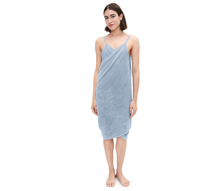 Žena stojí a má na sobě světle modré ručníkové šaty.