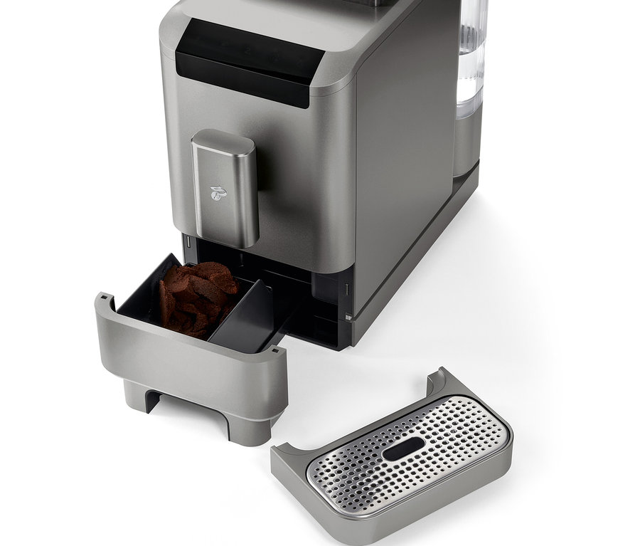 Detail plnoautomatického kávovaru »Esperto2 Caffè« v titanově stříbrné barvě s vyjmutou nádobou na kávovou sedlinu a odkapávací miskou.