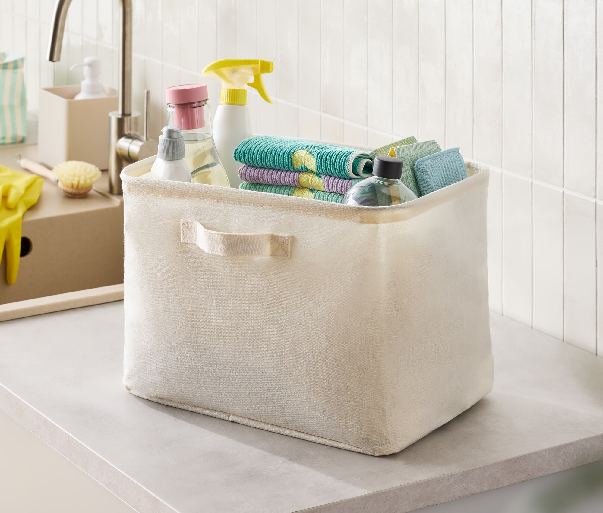 Béžový látkový box s čisticími prostředky a hadry na desce.