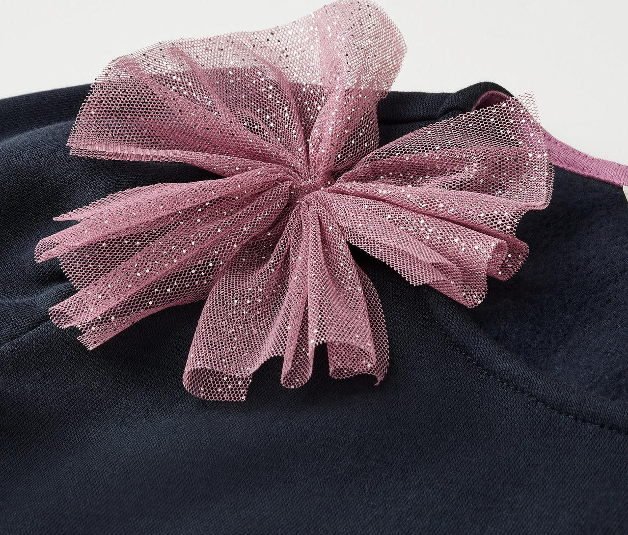 Tmavě modré oblečení s růžovou mašlí.