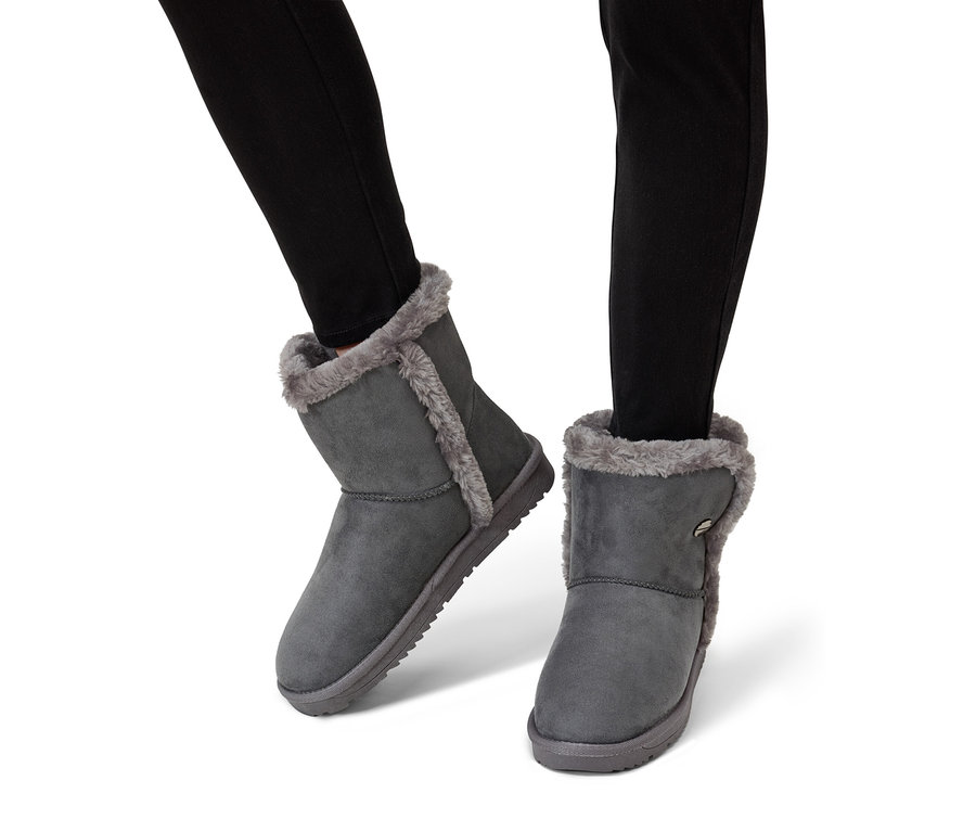 Nohy v černých džínách obuté v šedých kotníkových botách s kožešinovou podšívkou.