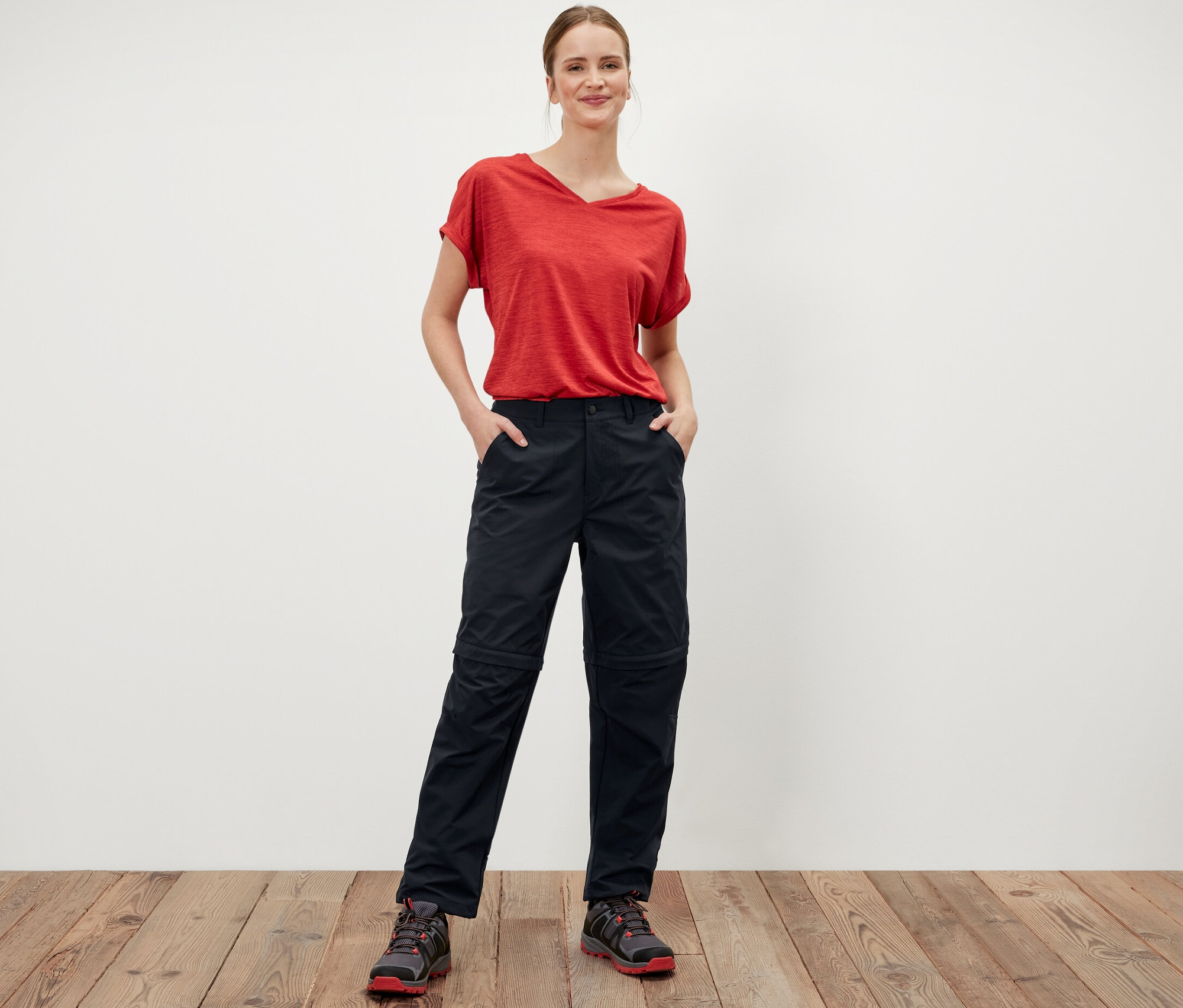 Žena stojí a má ruce v kapsách černých funkčních kalhot 2 v 1.