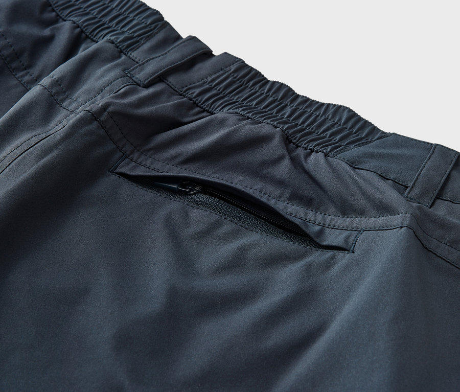 Detail modrých funkčních kalhot 2 v 1 s elastickým pasem a kapsou na zip.