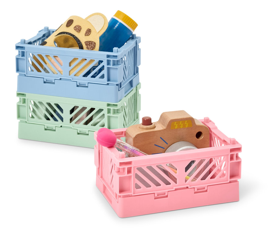 Stoh tří plastových přepravek různých barev, které obsahují hračky.