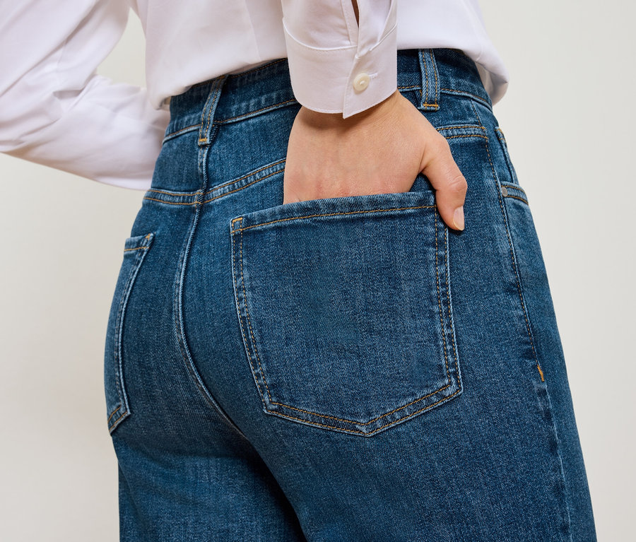Zadní pohled na ženu s rukou v kapse modrých Mom Jeans – Fit »Nyla«.