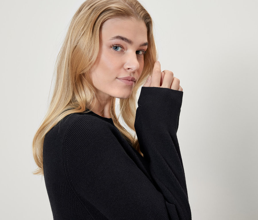 Portrét blondýny v černém svetru.