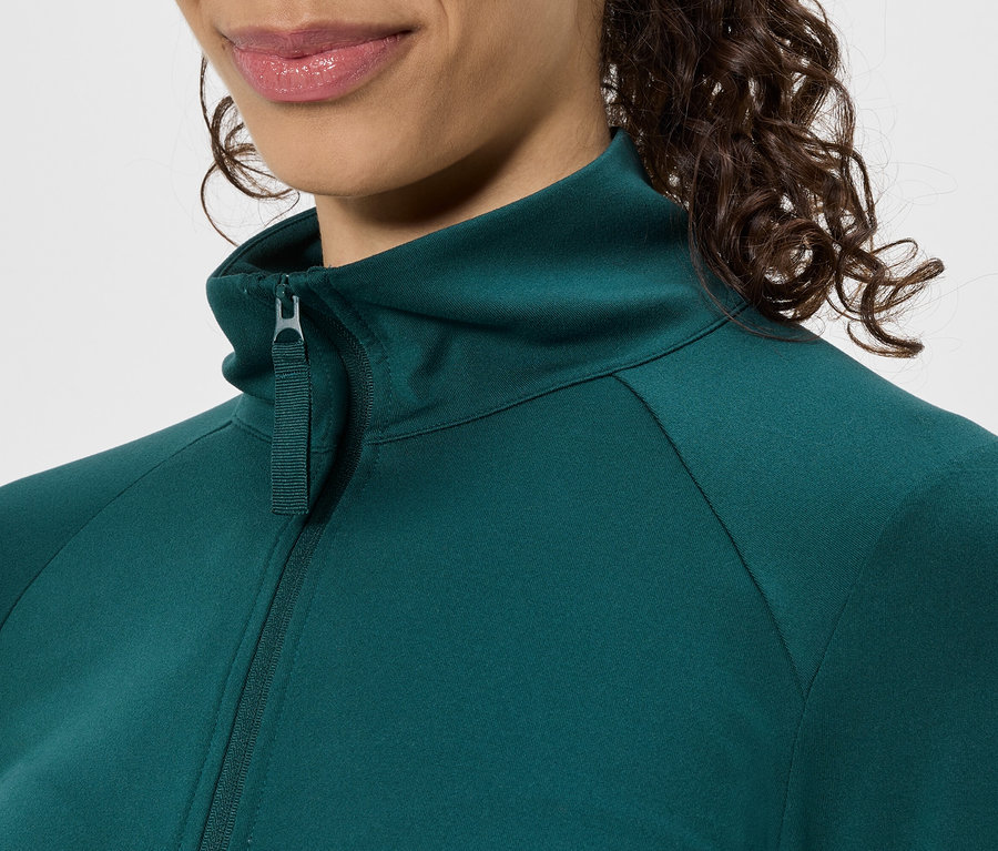 Detail ženy v zelené bundě na zip se stojáčkem.